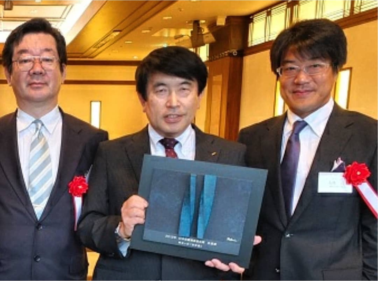露木保男氏と高橋治教授らがODBシステムの受賞記念盾を手にする写真。建築用オイルダンパー開発の歩みを伝える。